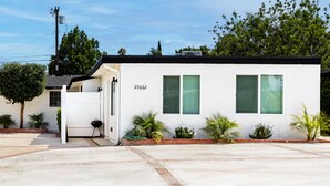 A single-story house with a white exterior, numbered 20662, featuring a front porch, a small patio area, and a well-maintained lawn.