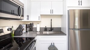 A modern kitchen with stainless steel appliances, white cabinetry, and a black stovetop.