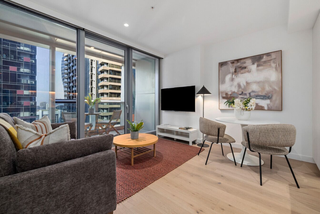 Un salon moderne avec un canapé, des fauteuils, une table basse et un téléviseur.