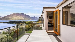 Ein modernes Haus mit einem Balkon mit Blick auf einen See und Berge.