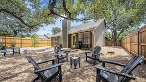 Un jardin avec des fauteuils Adirondack, un foyer et une terrasse en bois.