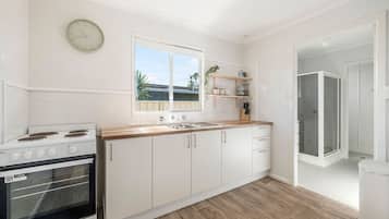 A modern kitchen with white cabinetry, a wooden countertop, a built-in oven, and a window with a view of the outside.