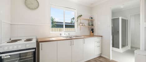 Een moderne keuken met witte kasten, een houten aanrecht, een ingebouwde oven en een raam met uitzicht.