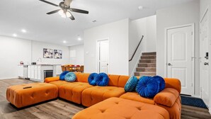 Ein modernes Wohnzimmer mit einer Eckcouch, einem Deckenventilator und einer Treppe zu einer anderen Ebene.