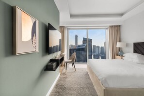 A hotel room with a large bed, a desk, a chair, a TV, and a view of the city skyline. - Luxury in Dubai Marina Dining Pool Day Beaches (Dubai)