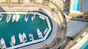 Vista aérea de un puerto deportivo con barcos amarrados, un área de piscina y un edificio con balcones.