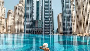 Une piscine avec une personne dans l’eau, entourée de grands immeubles.