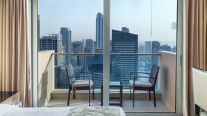 Un balcon avec vue sur la ville, deux chaises et un lit.