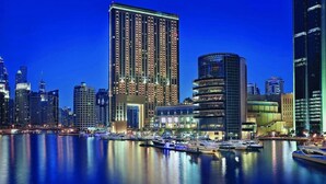 A waterfront cityscape with high-rise buildings, a marina with yachts, and a prominent hotel with a unique architectural design. - Amazing Views at The Address Dubai Marina (Dubai)