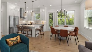 Una cocina moderna con armarios blancos, un refrigerador de acero inoxidable y una isla central con taburetes de bar.