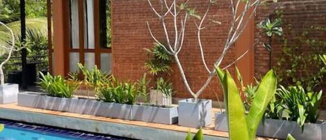 A modern two-story building with a brick facade and large windows. In front of the building is a swimming pool with a blue tiled pattern.