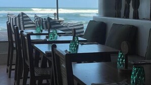 A dining area with tables and chairs, a large umbrella, and a view of the ocean. - Ko Lake Villa Rooms lakeside Beach (Koggala)