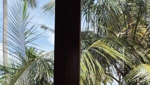 A view through a window with palm trees and a body of water in the background. - Ko Lake Villa Rooms lakeside Beach (Koggala)