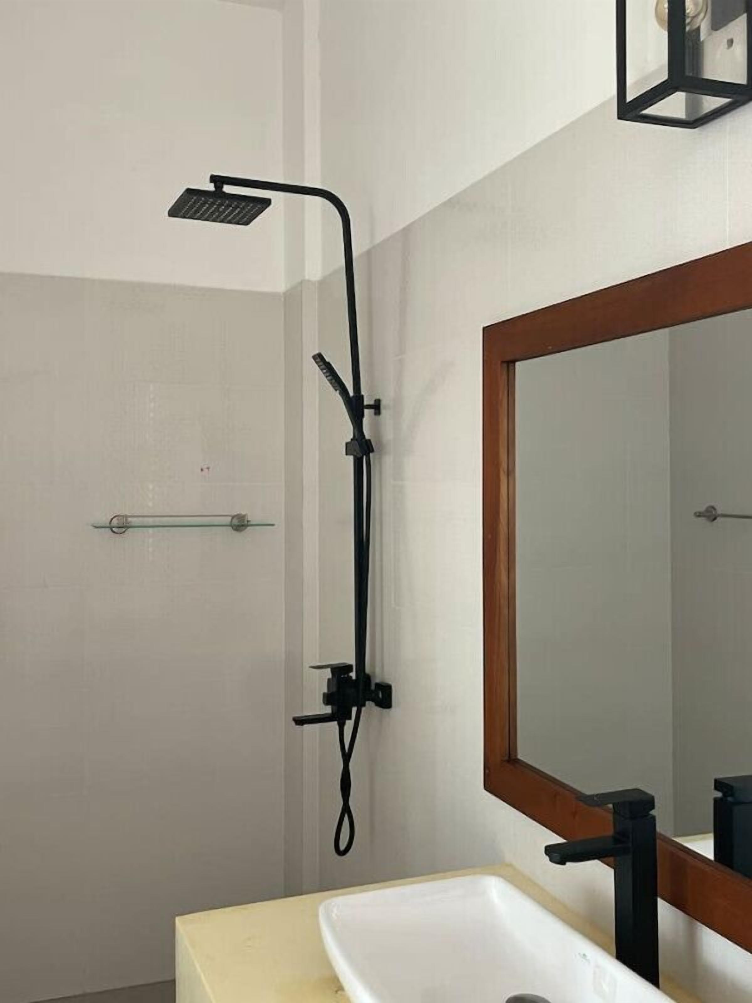 Un baño moderno con ducha, lavamanos y espejo.