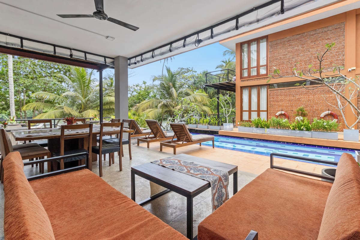 Un área de lounge exterior moderna con piscina, zona de comedor y asientos.