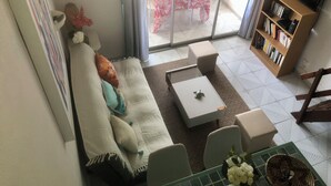 A living room with a sofa, a coffee table, a bookshelf, and a TV. - Charming Apartment in Creole Village of Trois-Ilets (Les Trois-Îlets)