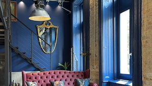 A modern living room with a red sofa, a wooden coffee table, and a large window with blue walls.
