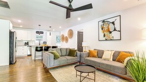 A modern living room with a grey sofa, a coffee table, and a dining area with a kitchen in the background. - 5 Mi to Dtwn Atlanta: Family Home w/ Fenced Yard (Atlanta)