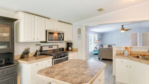 A modern kitchen with white cabinetry, a granite countertop, and a central island. - 2 Blocks to Beach! Family-friendly Home in PCB (Panama City Beach)