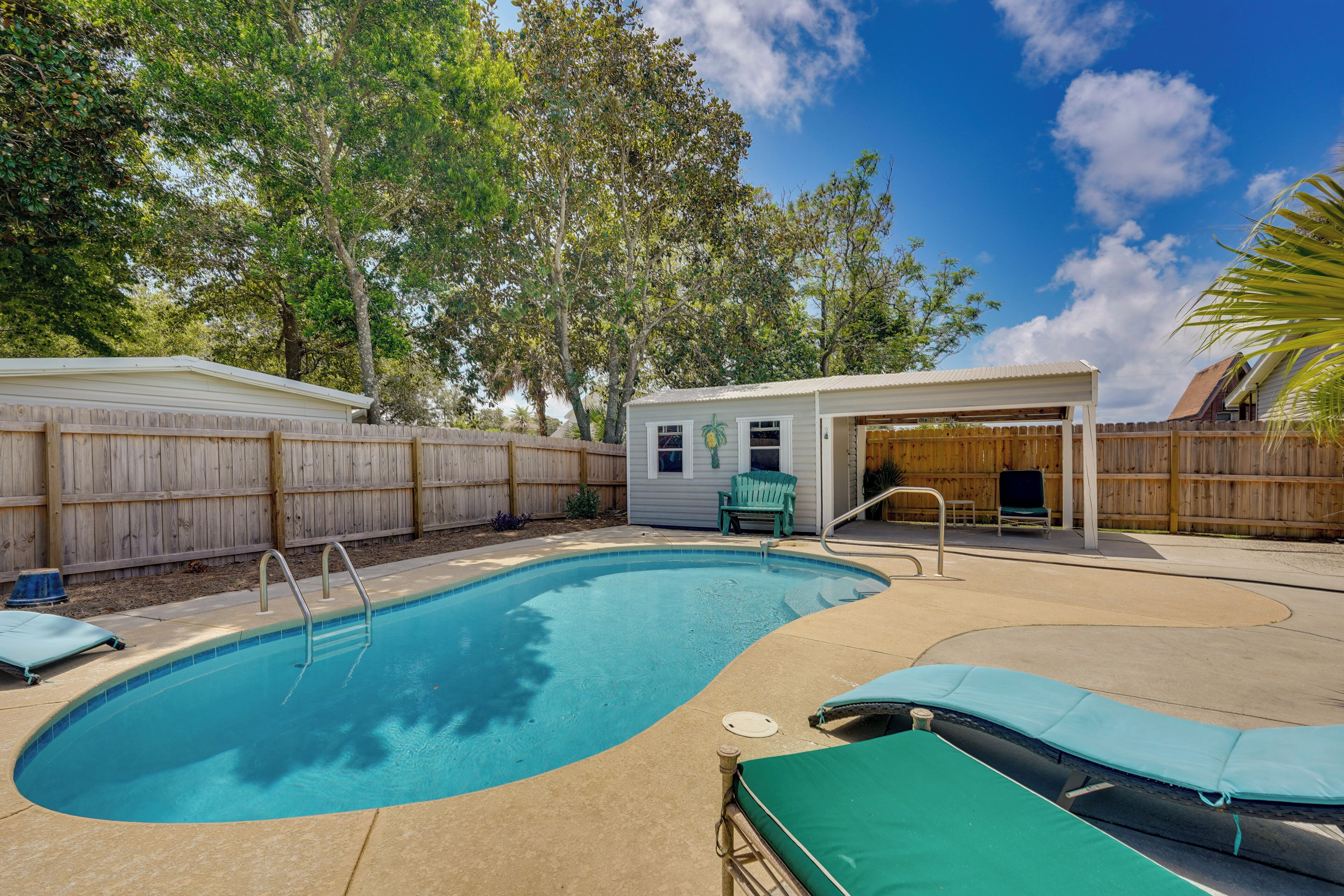 Un jardin avec une piscine, un patio couvert et une clôture en bois.