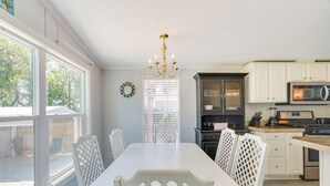 A kitchen with white cabinetry, a dining table with chairs, a chandelier, and a view of the outdoors. - 2 Blocks to Beach! Family-friendly Home in PCB (Panama City Beach)