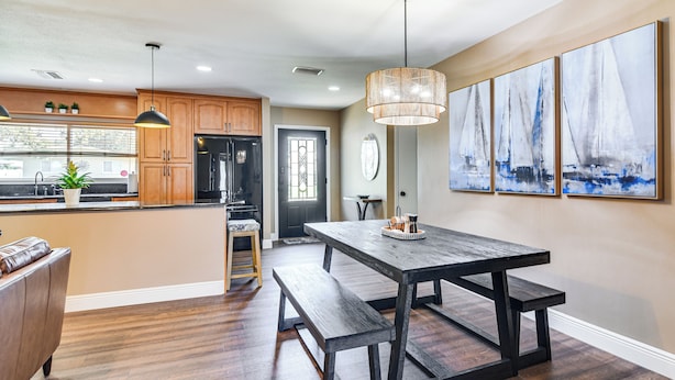 A modern kitchen with wooden cabinets, a central island, and a dining area with a bench.