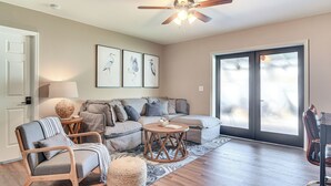 A living room with a sofa, armchairs, a coffee table, and a ceiling fan.