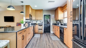 A modern kitchen with wooden cabinets, granite countertops, and stainless steel appliances.