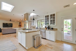 A modern kitchen with a central island, built-in appliances, and a large window.