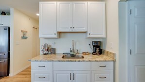A kitchen with white cabinets, a granite countertop, a stainless steel sink, and a coffee maker. - Heated Pool + Lanai: Peaceful Punta Gorda Stay (Punta Gorda)