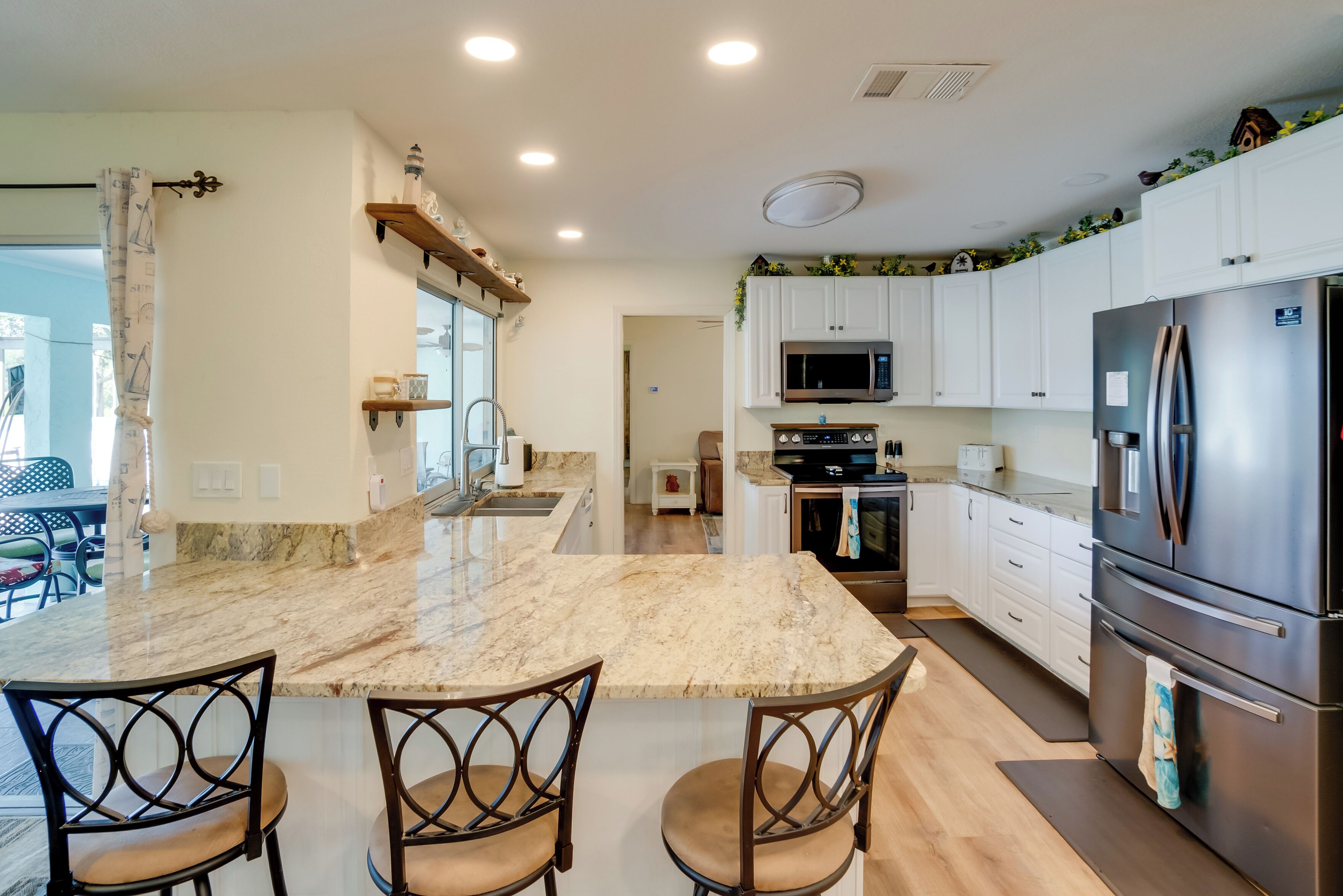 A modern kitchen with a marble island, stainless steel appliances, and white cabinetry.
