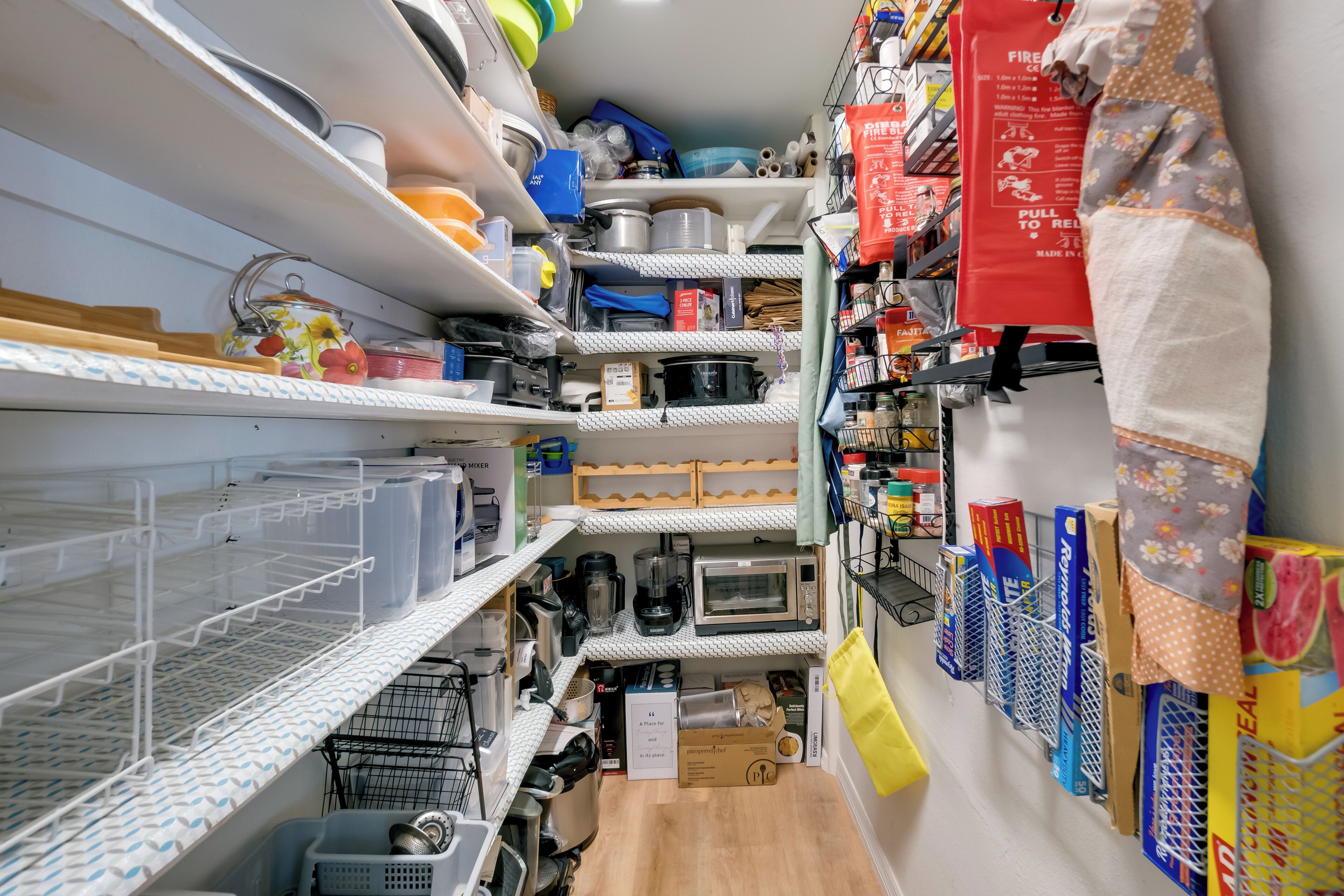 A kitchen with shelves, appliances, and storage containers.