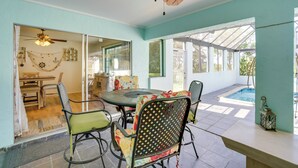 A sunlit patio with a table and chairs, a ceiling fan, and a view of a swimming pool. - Heated Pool + Lanai: Peaceful Punta Gorda Stay (Punta Gorda)