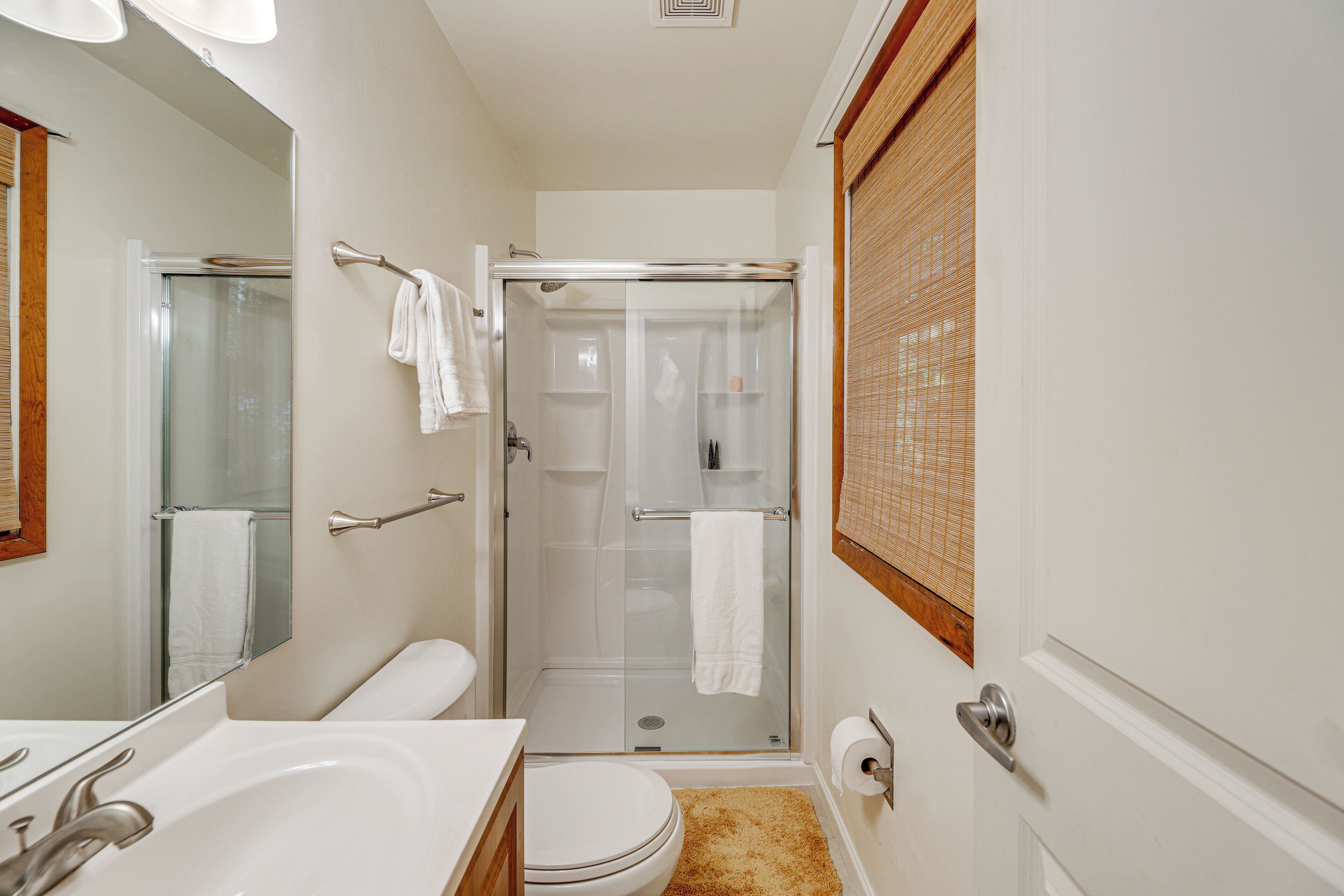 A bathroom with a glass-enclosed shower, a toilet, and a sink.