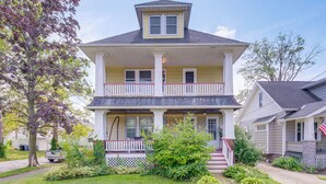 Une maison à deux étages avec un porche à l’avant, un petit jardin et une allée.