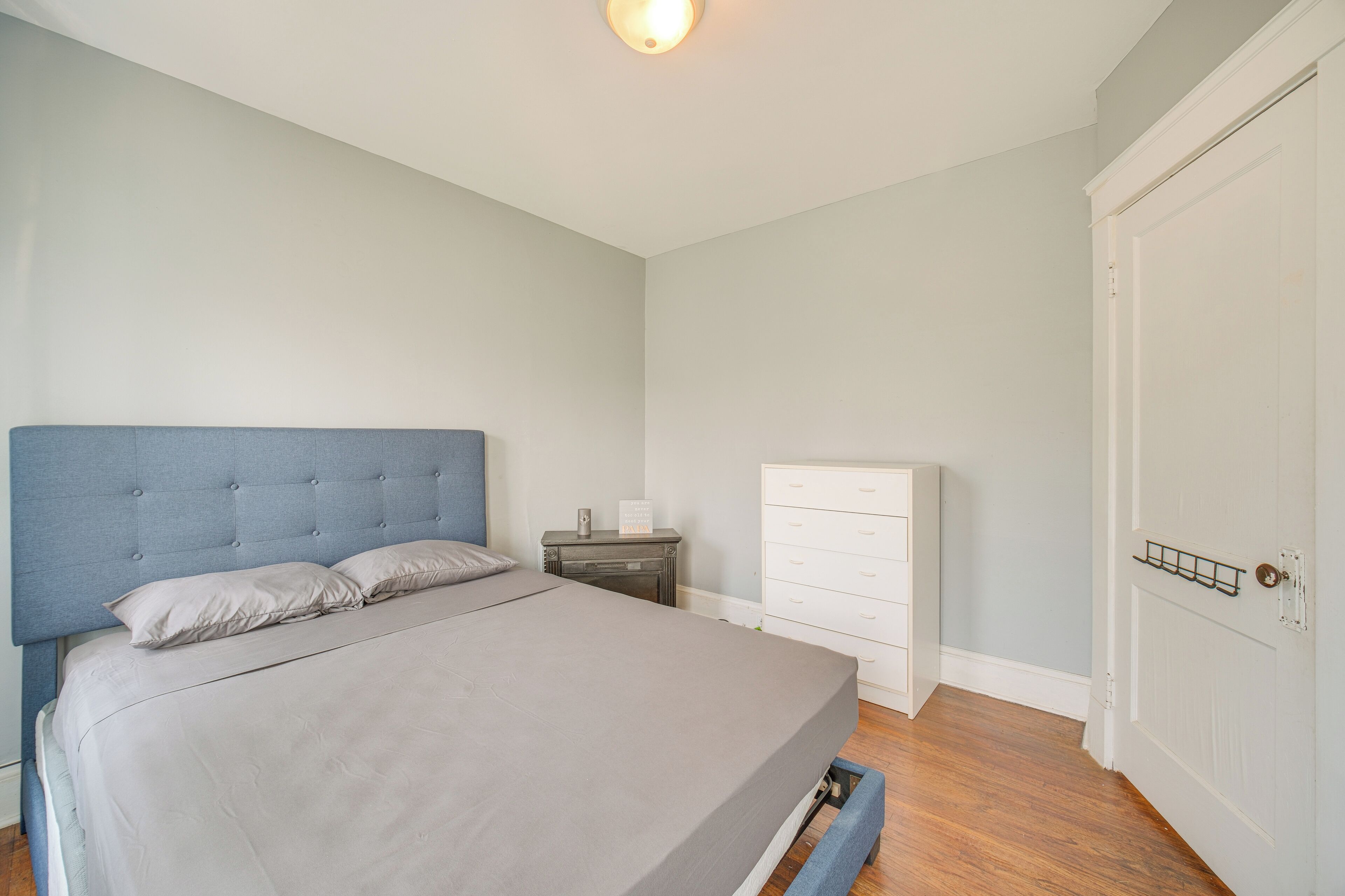 A bedroom with a bed, a dresser, a nightstand, and a door.