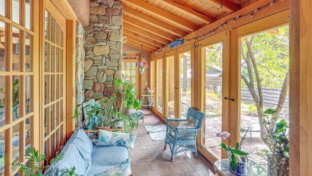 A covered patio with wooden beams, stone walls, and large windows. - Steps From Natl Forest: Creekside Home in Durango (Durango)