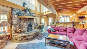 A spacious living room with a stone fireplace, wooden beams, a pink sofa, and a dining area. - Steps From Natl Forest: Creekside Home in Durango (Durango)