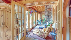 A spacious room with a stone wall, wooden ceiling beams, and a large window. - Steps From Natl Forest: Creekside Home in Durango (Durango)