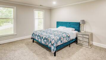 A bedroom with a bed, a nightstand, and two windows.