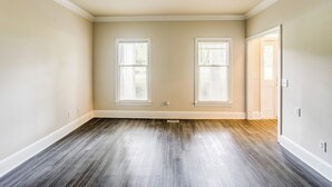 A room with two windows, a wooden floor, and a door leading to another room. - 3-story Home w/ Private Backyard in Florence! (Florence)