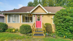A yellow house with a red door, a front porch, and a small garden. - 2 Mi to Hiking Trails: Cozy Fayetteville Cottage! (Fayetteville)