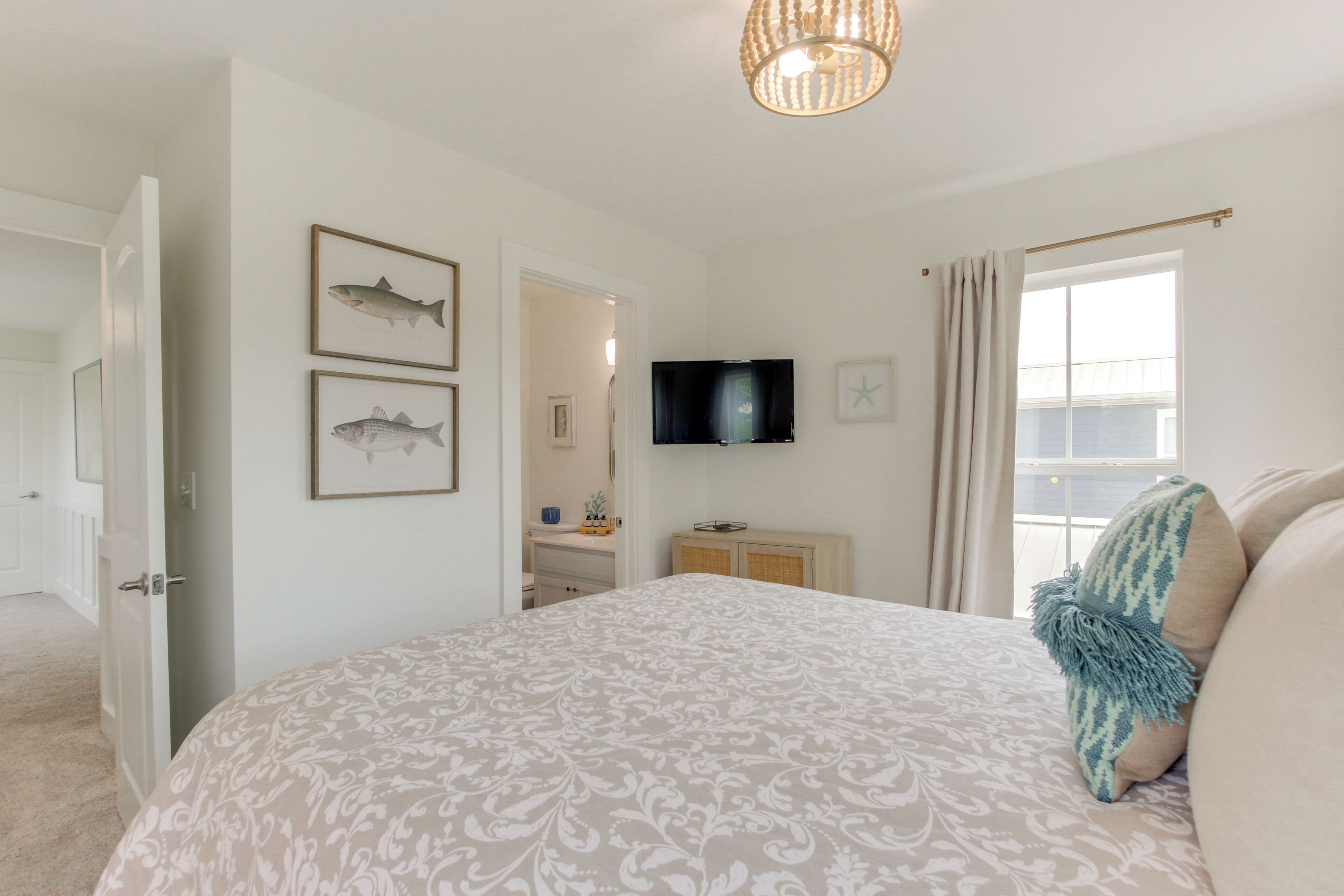 A bedroom with a bed, a television, and framed fish illustrations on the wall.