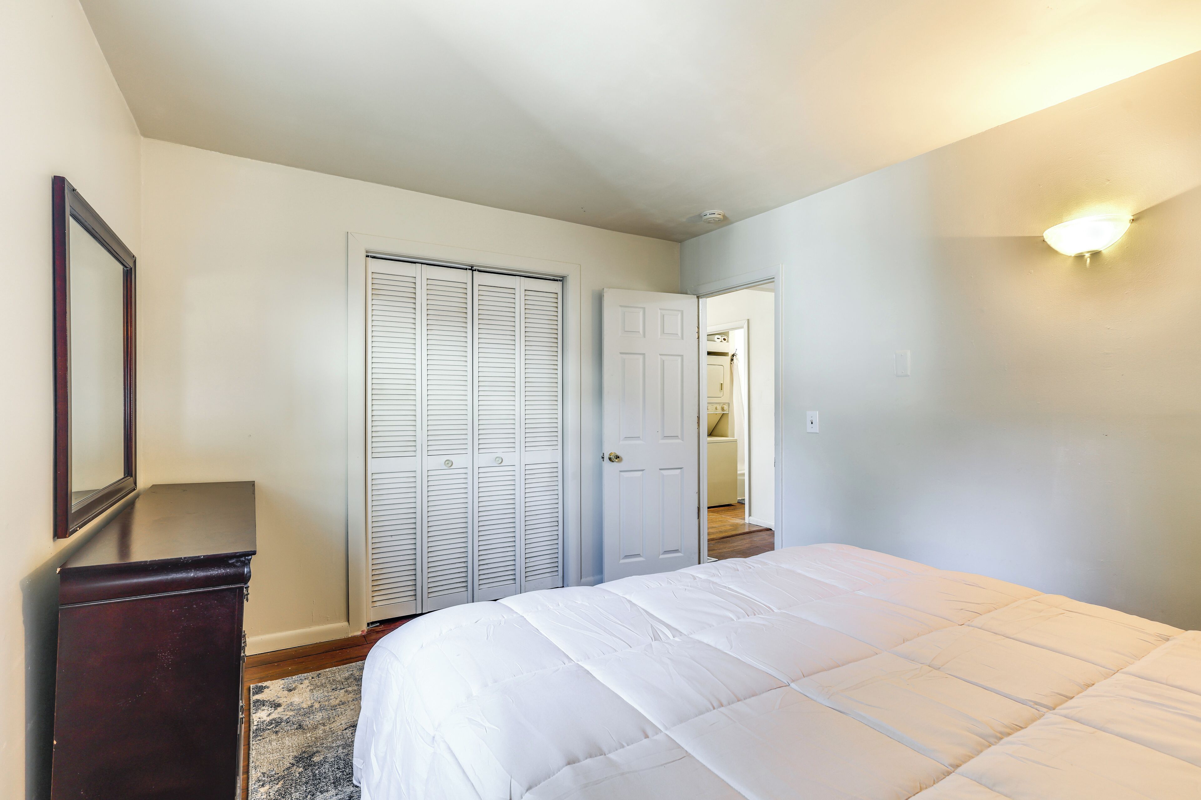 A bedroom with a bed, a dresser, and a closet.