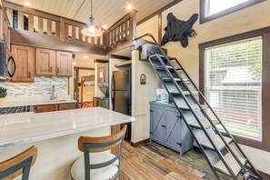A kitchen with a marble countertop, wooden cabinets, a stainless steel refrigerator, and a wooden staircase. - 1 Mi to Tank Town Usa: Tiny Home w/ Pool Access! (Morganton)