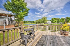 A wooden deck with a table and chairs, overlooking a lake and a residential area. - 1 Mi to Tank Town Usa: Tiny Home w/ Pool Access! (Morganton)