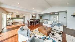 A spacious living room with a wooden coffee table, a grey sofa, and a patterned rug. - Waterfront Home w/ Dock, Hot Tub, Fire Pit (Oak Harbor)