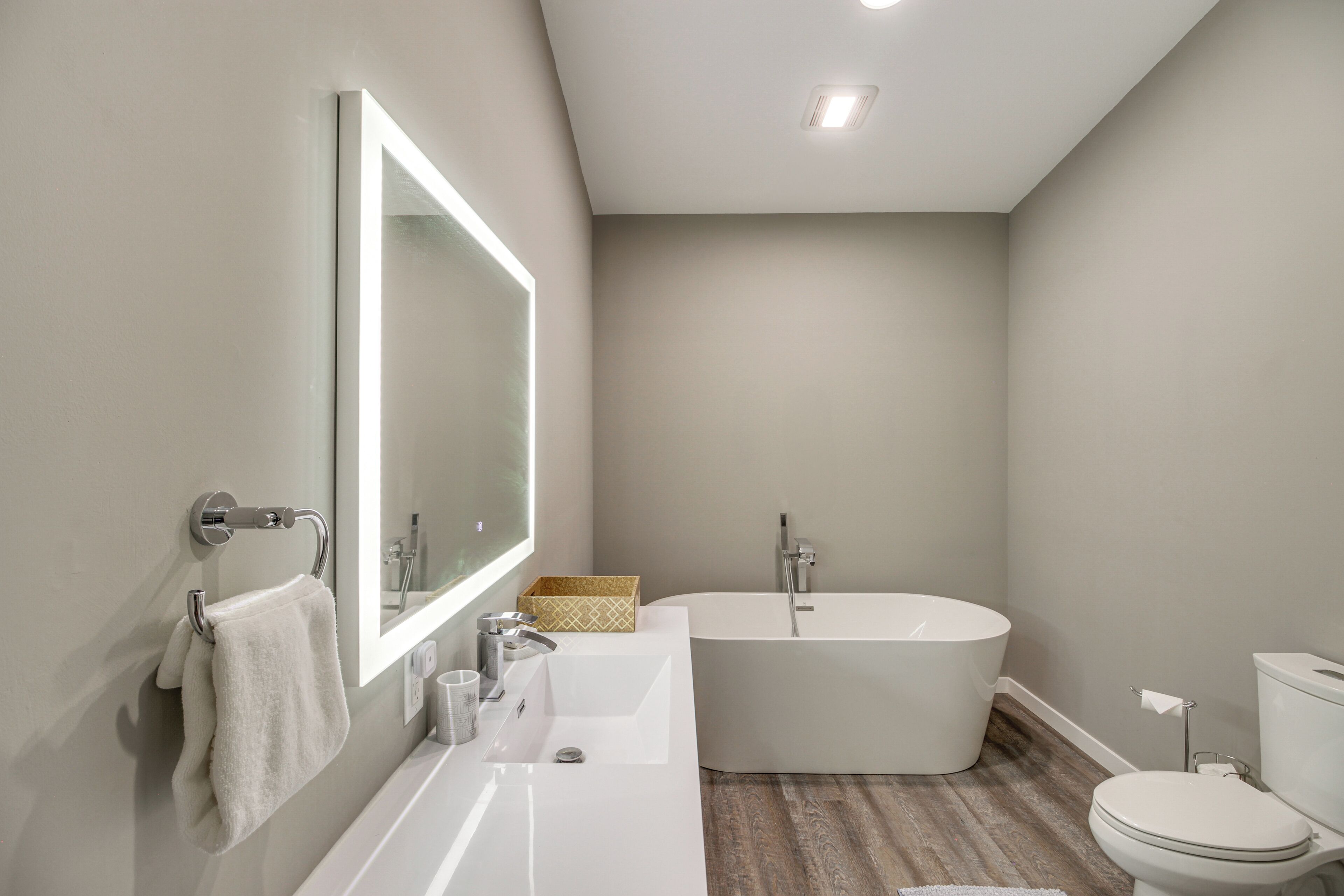 A modern bathroom with a large bathtub, a separate sink, and a toilet.