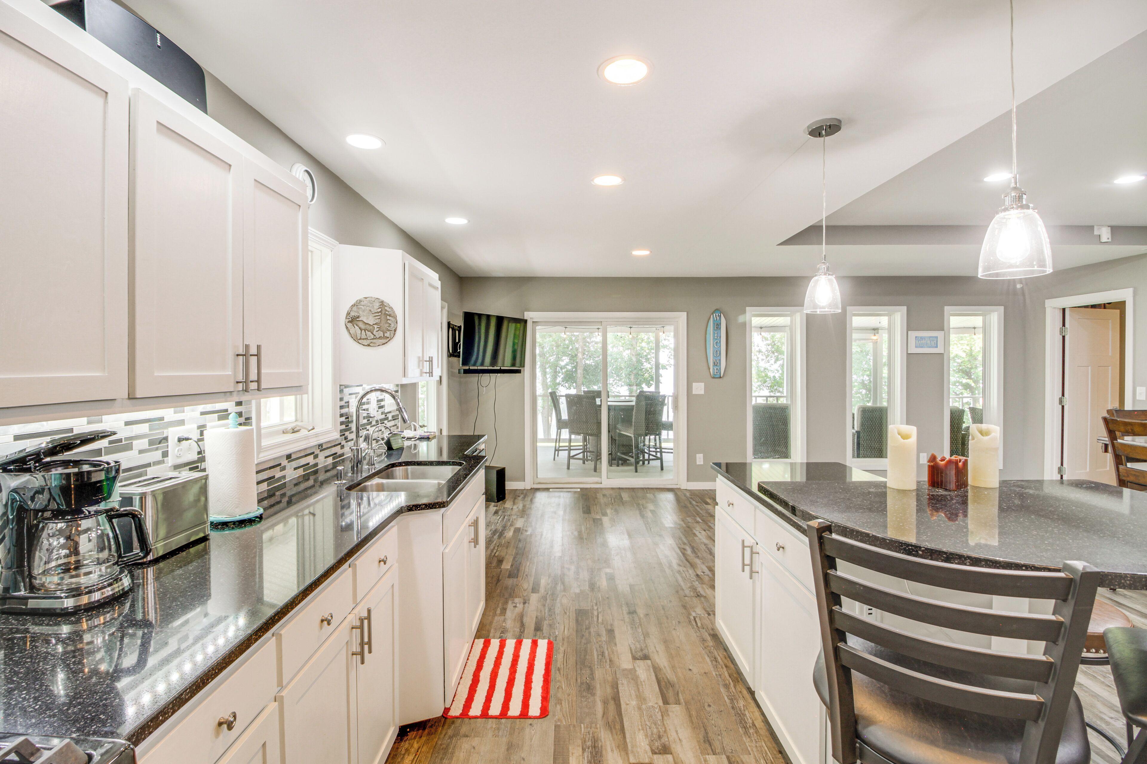 A modern kitchen with white cabinets, a granite countertop, and a dining area with a table and chairs.