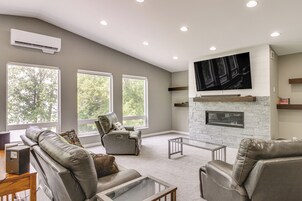 A spacious living room with a fireplace, leather sofas, and a large TV mounted on the wall.